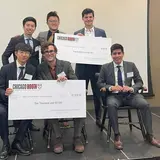 Five people wearing suits and holding two oversized checks