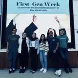 Six people standing in front of a digital screen that says “First Gen Week”